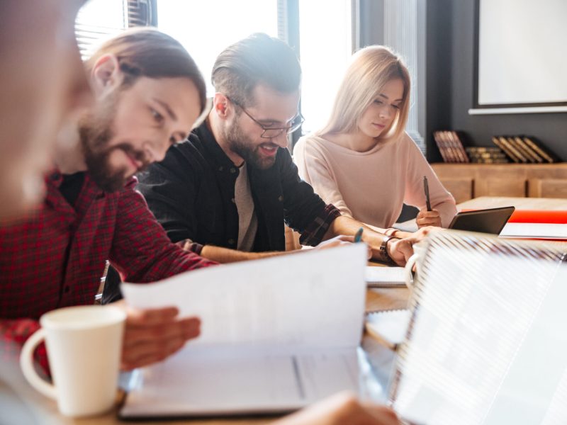 Photo of young happy colleagues sitting in office and coworking.